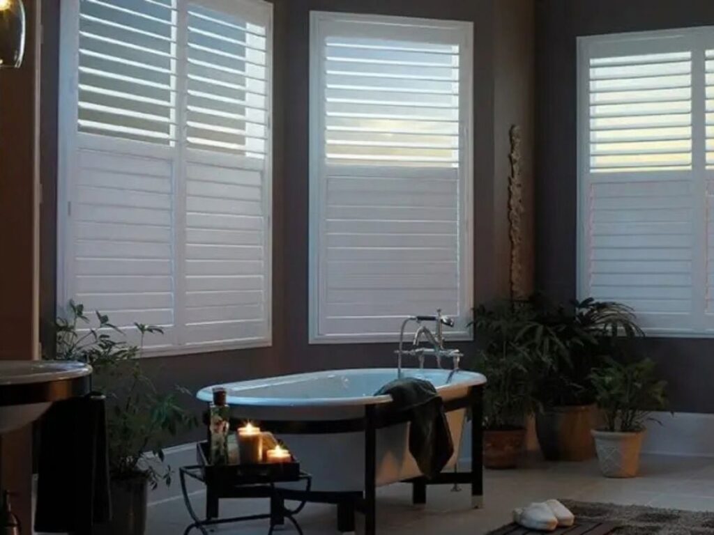 This is a photo of a white full-height shutters in a bathroom with bathtub