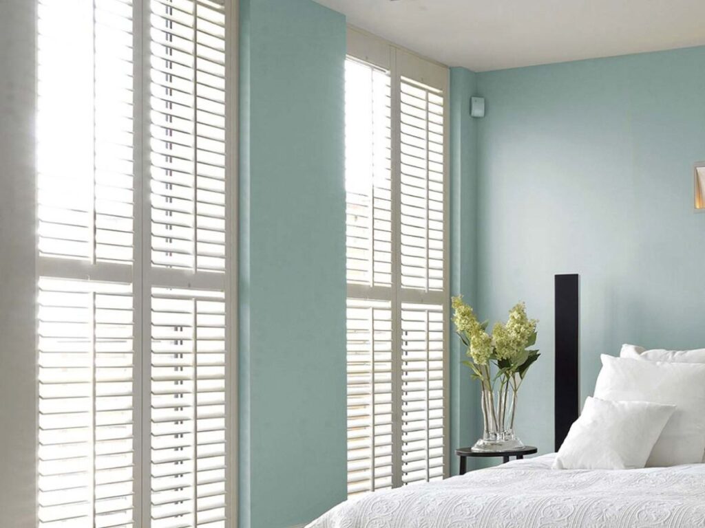 This is a photo of a white full-height shutters in a bedroom